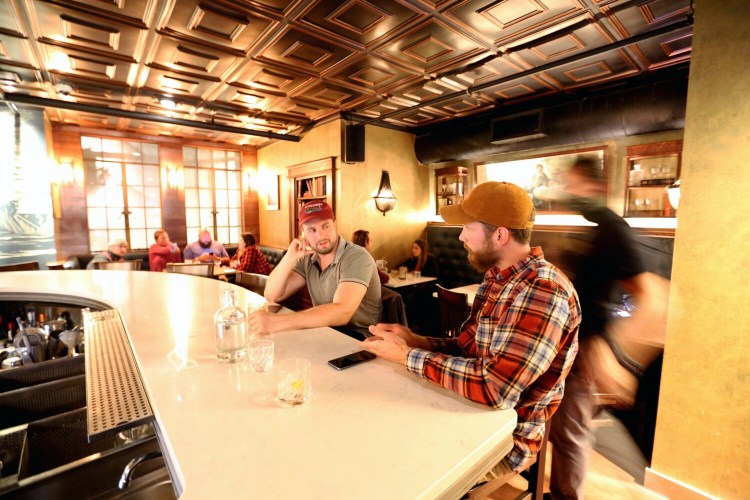 C.J. Cerio, left, and Nick Grasso of Elmira, New York, prepare to order another round at Blyth & Burrows in Portland on Thursday. While many bars in Maine are still prohibited from operating, those with kitchens have reopened and are hoping to survive the winter.