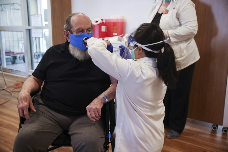 U.S. Air Force Veteran Robert Aucoin, 78, receives a COVID-19 vaccine dose at the Soldiers' Home in Holyoke, Mass., on Tuesday.