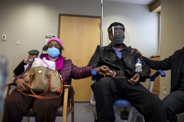 Dorothy Kade, left, holds the hand of her husband, Walter Kade Jr., as they wait in the observation room after he received a COVID-19 vaccine at the VA Medical Center in Philadelphia on Saturday.
