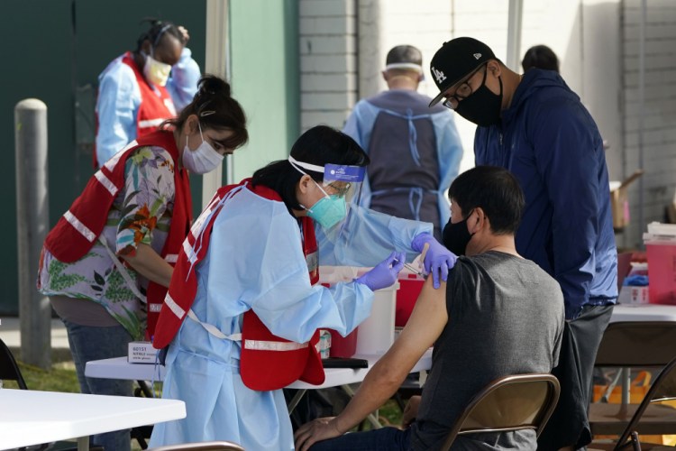 FILE - In this Jan. 13, 2021, file photo, health care workers receive a COVID-19 vaccination at Ritchie Valens Recreation Center, Wednesday, Jan. 13, in Pacoima, Calif. The rapid expansion of vaccinations to senior citizens across the U.S. has led to bottlenecks, system crashes and hard feelings in many states because of overwhelming demand for the shots. 