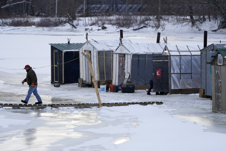 Clem Tome walks cross a temporary bridge on the ice at Leighton's Smelt Camps, Wednesday, Feb. 10, in Bowdoinham. A lack of ice in cold weather states this year has made it difficult for scientists to study the rainbow smelt population. 