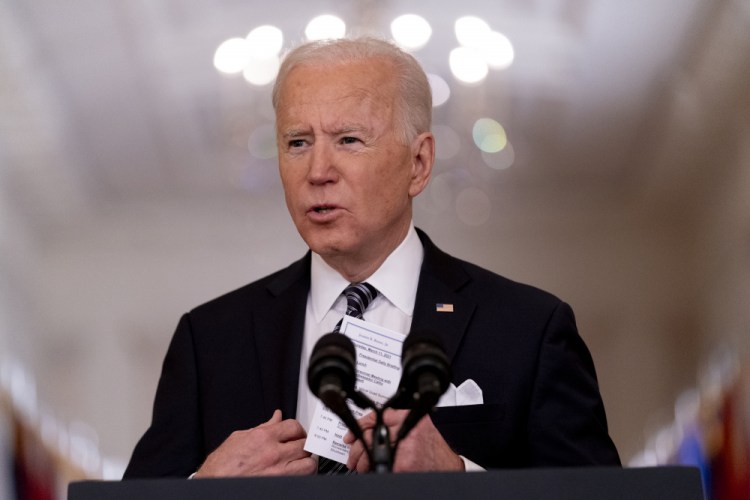 President Biden holds up a card with his daily schedule and the daily deaths from COVID-19 on March 11 during a primetime address from the East Room of the White House. “He ran as the antithesis of Trump," said former Barack Obama adviser David Axelrod. "Empathetic, decent and experienced, and he is delivering." 
