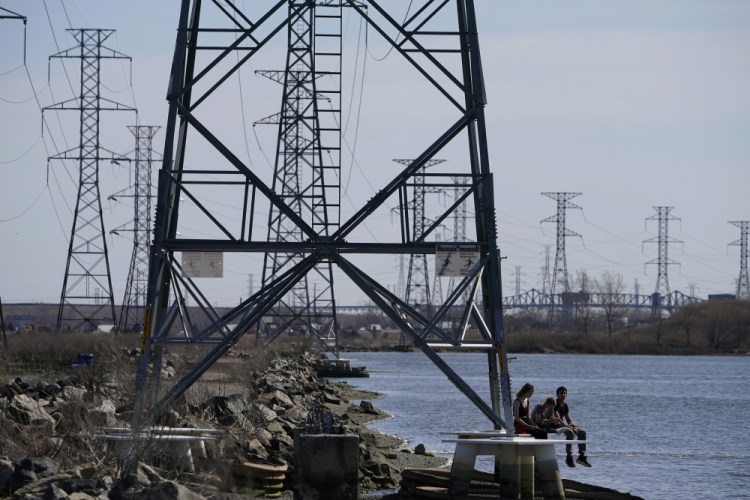 People sit at the base of a transmission tower in North Arlington, N.J. The U.S. electricity system relies on about 600,000 miles of transmission lines, but it can take years to get new ones approved. 
