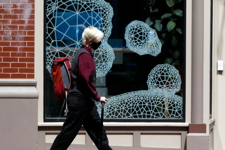 A mask-wearing person walks down Congress Street on June 3. 