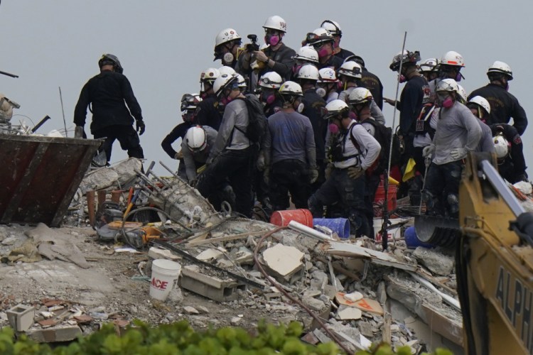 Search and rescue personnel work Wednesday atop the rubble at the Champlain Towers South condo building, where scores of people remain missing almost a week after it partially collapsed. 