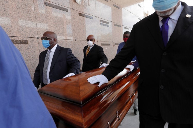 FILE - In this April 22, 2020, file photo, pallbearers, who were among only 10 allowed mourners, walk the casket for internment at the funeral for Larry Hammond, who died from the coronavirus, at Mount Olivet Cemetery in New Orleans. Government health officials say Native Americans, Latinos and Black people are two to three times more likely than whites to die of COVID-19. 