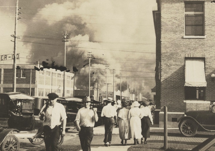 Two armed men walk away from burning buildings as others walk in the opposite direction during the June 1, 1921, race massacre in Tulsa, Okla. 