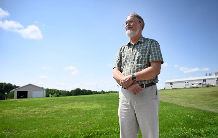 FAIRFIELD, ME - JULY 15: Nathan Saunders whose well was contaminated from sludge that was spread on nearby fields poses in front of the field located directly across the street from his home Thursday July 15, 2021. (Staff Photo by Shawn Patrick Ouellette/Staff Photographer)