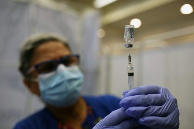 PORTLAND, ME - JULY 15: Parivash Rohani, a retired registered nurse working on assignment for the Maine Department of Health and Human Services, prepares a syringe of the Johnson & Johnson COVID-19 vaccine at a free, no-appointment clinic at Portland International Jetport on Thursday. Rohani came out of retirement because she "wanted to be part of this historic time." (Staff photo by Ben McCanna/Staff Photographer)