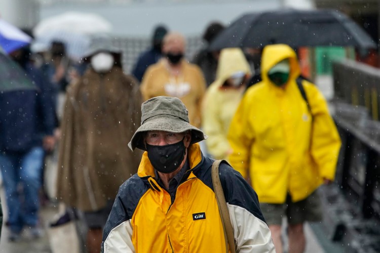 Ferry passengers disembark in the rain from Tropical Storm Elsa, Friday, July 9, 2021, in Portland, Maine. (AP Photo/Robert F. Bukaty)