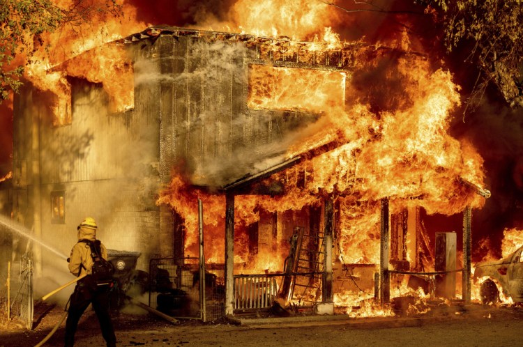 A firefighter sprays water while trying to stop the Sugar Fire, part of the Beckwourth Complex Fire, from spreading to neighboring homes in Doyle, Calif. on Saturday (AP Photo/Noah Berger)