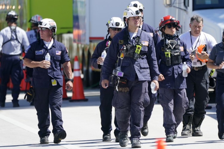 Members of the South Florida Urban Search and Rescue team walk near the Champlain Towers South condo building, where scores of victims remain missing more than a week after it partially collapsed, Saturday in Surfside, Fla.


