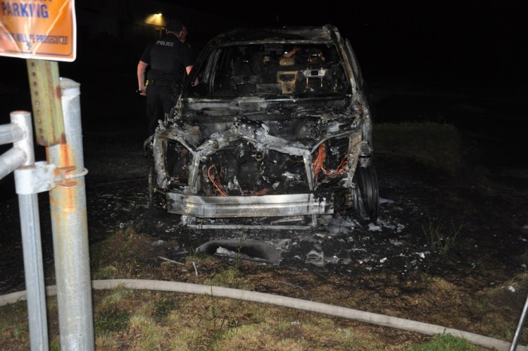 Lewiston police inspect a burned car July 7 at The Colisee on Birch Street.