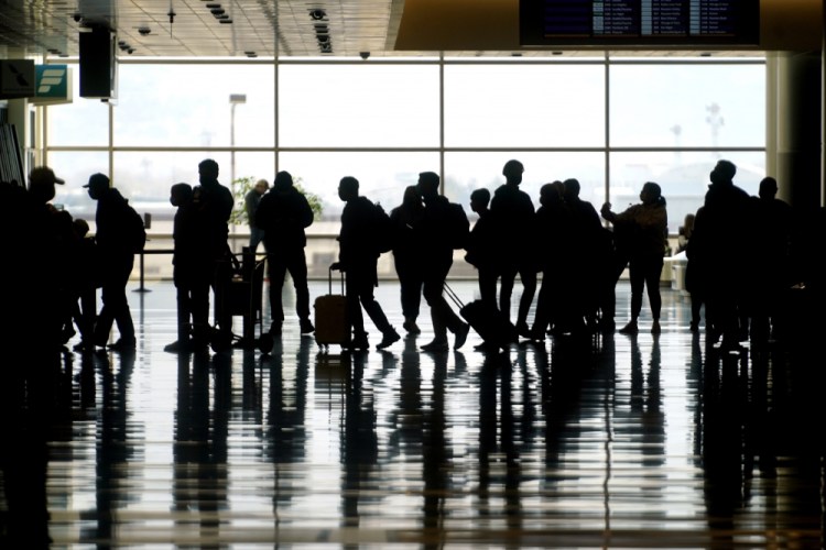 Travelers walk through the Salt Lake City International Airport in Salt Lake City in March. The U.S. will keep existing COVID-19 travel restrictions on international travel in place for now. 