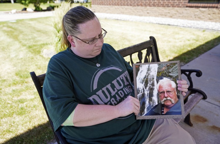 Ann Haas poses June 18 in Eden Prairie, Minn., with a photo she took of her late father, Raymond Haas. Haas lost her father to COVID-19 on Nov. 11 and works in the laundry at the same Veterans Affairs hospital where he spent his final days. Haas said memories coming flooding back each time she folds a tan blanket like the one that covered him while he was fighting to live. 


