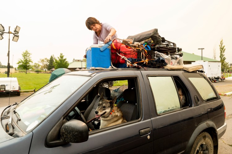 Greenville resident Kesia Studebaker, who lost her home to the Dixie Fire, secures belongings before leaving a Susanville, Calif., evacuee shelter with her dog Logan on Friday, Aug. 6, 2021. "I lost everything. This is all I've got," said Studebaker adding "It's a new beginning, a new adventure." She was heading out to stay with friends nearby. (AP Photo/Noah Berger)