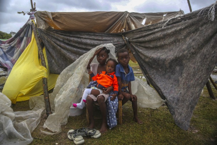Children displaced by the earthquake huddle under a piece of plastic the morning after Tropical Storm Grace swept over Les Cayes, Haiti, on Tuesday, three days after a 7.2-magnitude earthquake. 