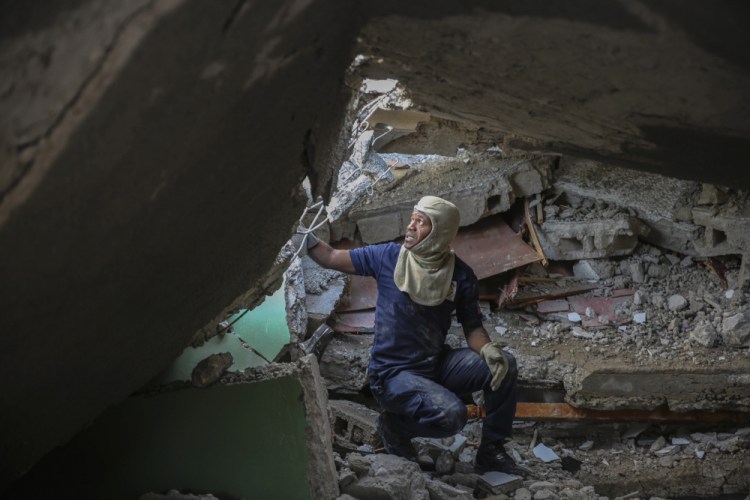 A firefighter searches for survivors Sunday inside a damaged building, after Saturday's 7.2 magnitude earthquake in Les Cayes, Haiti.