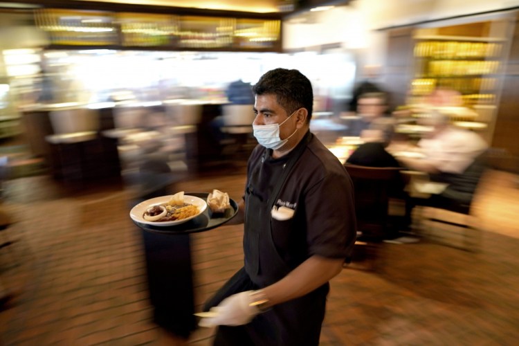 Marcelino Flores delivers food to a table at Picos restaurant in Houston in March. 

