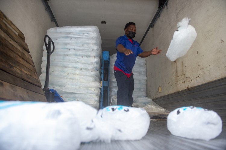 John Smith of Pelican Ice tosses bags of ice to the end of a truck as he helps stock a gas station in Jefferson, La., where residents were preparing for Hurricane Ida on Friday. Forecasters say Ida could be a major Category 3 hurricane with top winds of 115 mph when it nears the U.S. coast.