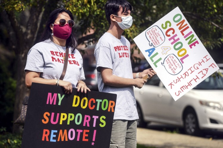 Macy Schulman, left, and Mason Yeoh, both students at Fairfield Warde High School, carry pro-remote learning signs during a rally of parents and students fighting to have an online option for school this year, Monday in Fairfield, Conn.