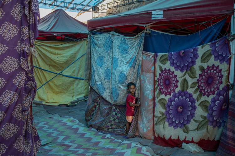 A young Rohingya refugee boy stands outside a tent at a refugee camp alongside the banks of the Yamuna River in the southeastern borders of New Delhi on July 1. India has been plagued by vaccine shortages.