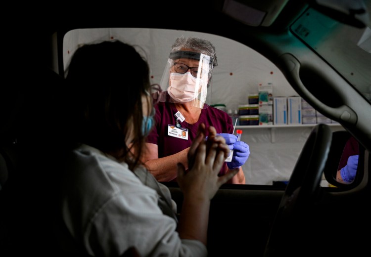 Donna Carpenter, lab assistant with Northern Light Mercy Hospital, goes over instructions on how to use a specimen collection kit with Matanah Betko of Portland at the COVID-19 drive up testing clinic at the hospital's Fore River Parkway campus Friday. 