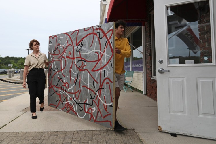 Lauren Donovan, left, and Kennan Hendricks, employees at Moss Galleries, move "Cedar St." a mixed-media on canvas painting by the late New York artist Michael Mulhern. Mulhern had a studio near the World Trade Centers and mixed ash from the fallen towers into his paint after the towers collapsed, blowing out his windows and filling his space with dust. Moss Galleries in Falmouth has acquired several paintings and is showing a variety of his work.