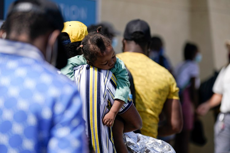 A young child sleeps on a migrant's shoulder after being released from United States Border Patrol custody at a humanitarian center, Wednesday, Sept. 22, 2021, in Del Rio, Texas. (AP Photo/Julio Cortez)