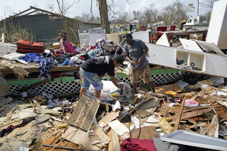 Cruz Palma, left, watches as her son, Jose Duran, center, and husband, Jose Garcia, work to remove a water heater from what's left of their home in the aftermath of Hurricane Ida, Thursday in Golden Meadow, La.
