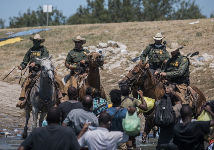 U.S. Customs and Border Protection mounted officers attempt to contain migrants as they cross the Rio Grande from Ciudad Acuña, Mexico, into Del Rio, Texas, on Sunday. Thousands of Haitian migrants have been arriving in Del Rio as authorities attempt to close the border to stop the flow of migrants. 