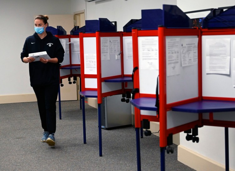Katie Mathews of Portland walks from the booths after voting absentee Wednesday at City Hall. Voters are returning to more normal habits of voting in person this year.