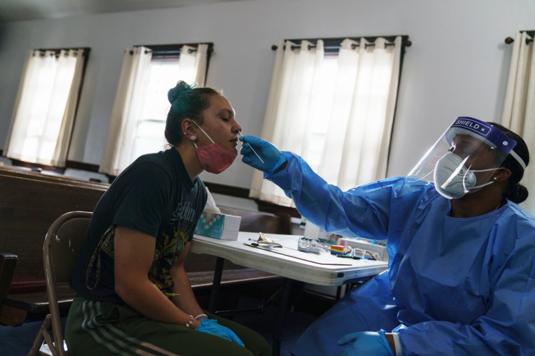 Jessica Leo, left, is tested for COVID-19 at a clinic set up at Bethel AME Church, Friday, Sept. 24, 2021, in Providence, R.I. Despite having some of the highest vaccination rates in the country, the New England states are still grappling with rapidly increasing COVID-19 case counts, hospitalizations and deaths. (AP Photo/David Goldman)