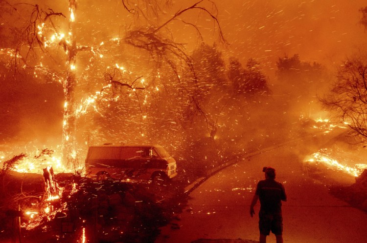 Bruce McDougal watches embers fly over his property as the Bond Fire burns through the Silverado community in Orange County, Calif., on Dec. 3, 2020. The United Nations on Monday released a new report on climate change. 