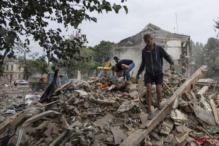 Local residents search for documents of their injured friend in the debris of a destroyed apartment house after Russian shelling Saturday in a residential area in Chuhuiv, Kharkiv region, Ukraine.