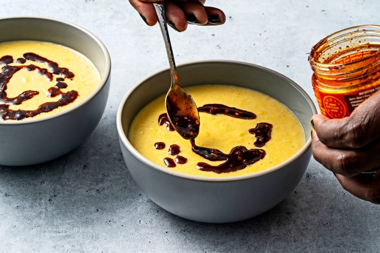 Swirling in the chili crisp for Coconut Corn Soup. MUST CREDIT: Photo for The Washington Post by Scott Suchman.