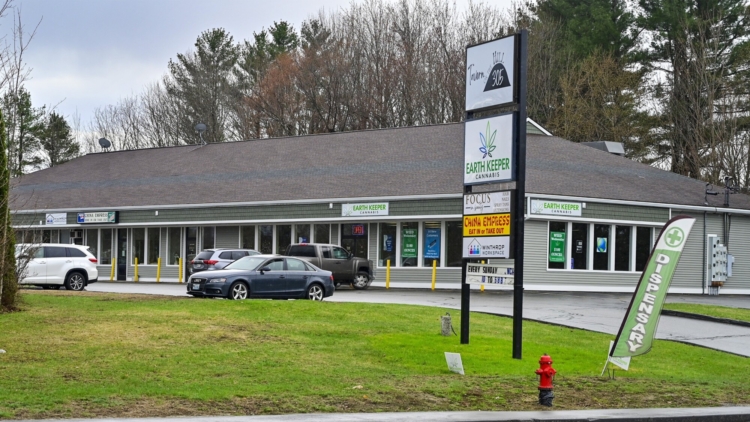 Exterior view of strip mall behind tall sign listing business names